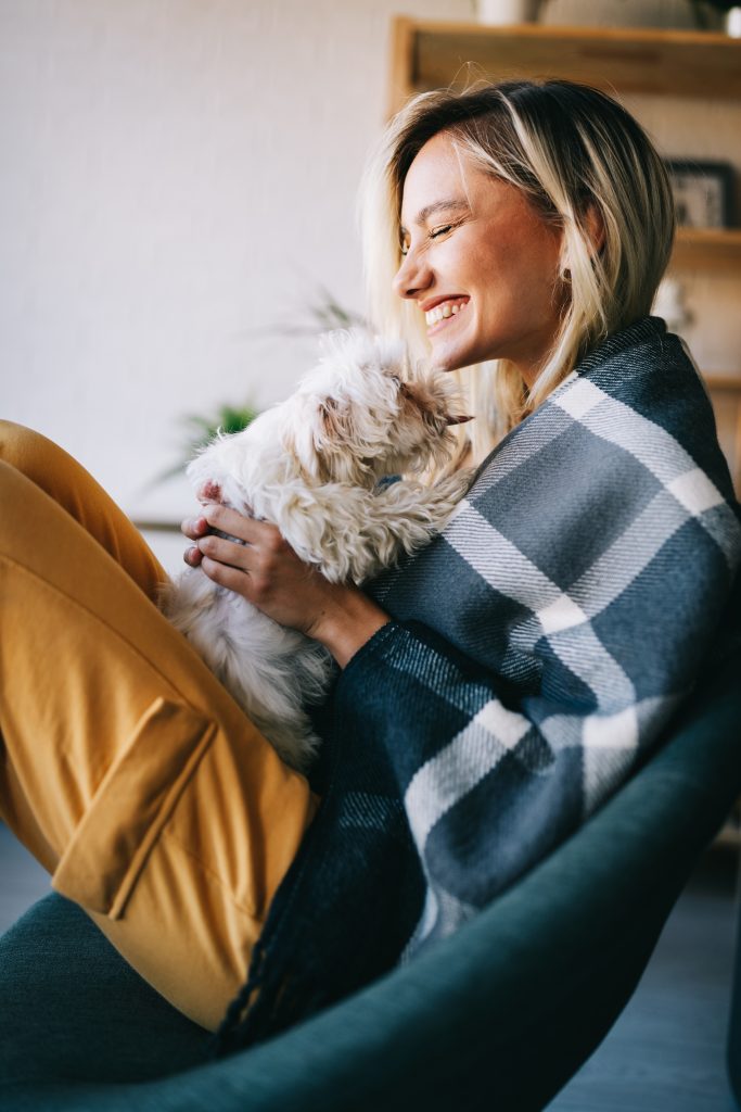 Woman cuddling with small white dog.